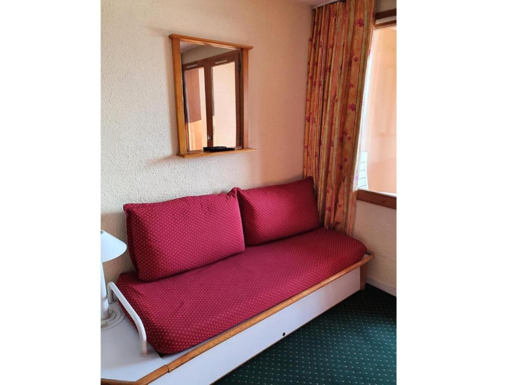 - un canapé rouge dans une pièce avec un miroir dans l'établissement Résidence Le Hameau du Sauget - maeva Home - 2 Pièces 4 Personnes Confort MAE-9861, à La Plagne Tarentaise