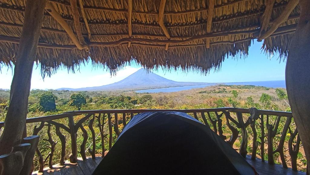 a person laying on a porch with a view of a mountain at Hostel & Camping Sol Y Luna Ometepe in Balgue