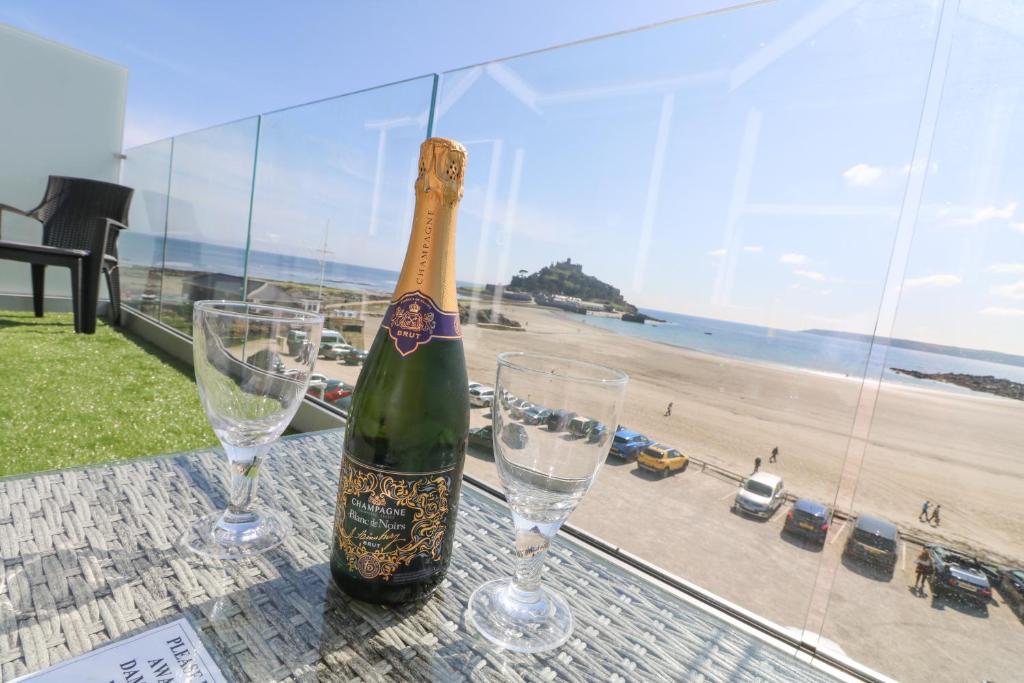 a bottle of champagne sitting on a table with two wine glasses at Higher Mount View in Marazion