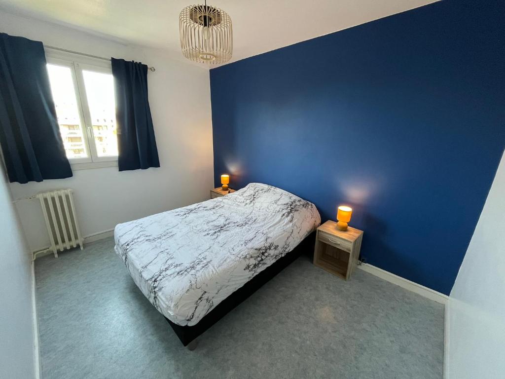 1 dormitorio azul con 1 cama y 2 velas en las mesas en Centre ville T2 - Aurillac - Parking Gratuit - Proche de la gare - 1 chambre - 1 canapé lit, en Aurillac