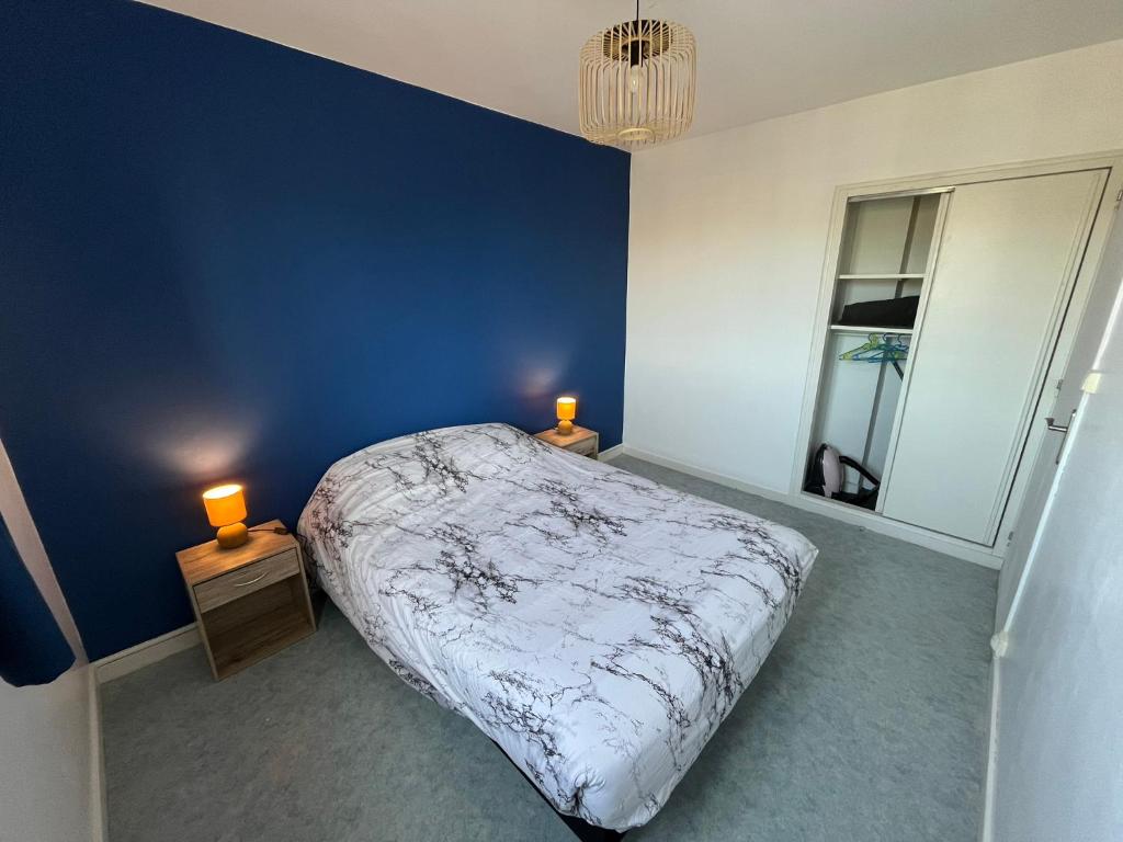 een blauwe slaapkamer met een bed en twee nachtkastjes bij Centre ville T2 - Aurillac - Parking Gratuit - Proche de la gare - 1 chambre - 1 canapé lit in Aurillac