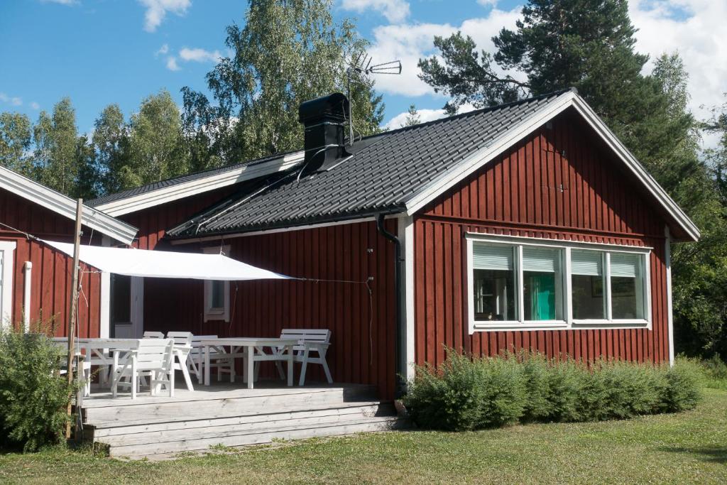een rood huisje met een tafel en stoelen op de veranda bij Kallrigafjärden nära Öregrund in Östhammar