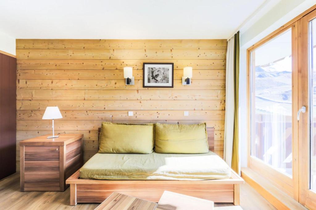 un lit dans une chambre avec un mur en bois dans l'établissement Résidence Les Temples du Soleil - maeva Home - Appartement 2 pièces 5 personnes Confort MAE-7729, à Val Thorens