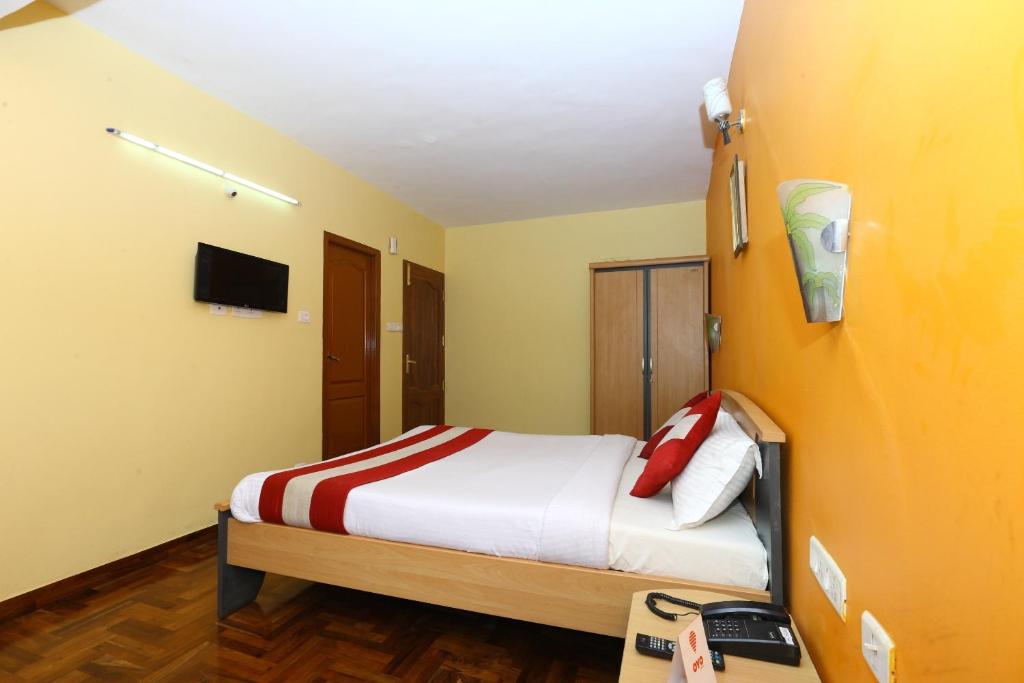 a bedroom with a bed and a tv on a wall at OYO Suba Krishmaa Residency in Kodaikānāl