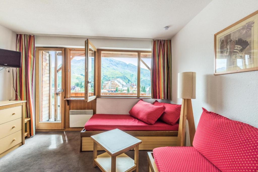 un salon avec un canapé rouge et des fenêtres dans l'établissement Résidence Les Fontaines Blanches - maeva Home - Appartement 2 pièces 7 personnes Confort MAE-7285, à Morzine