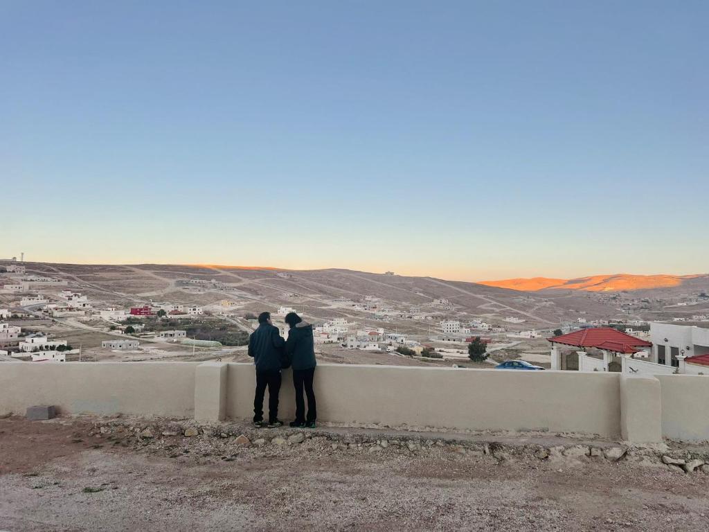 Due persone in piedi su un muro che guardano una città di Darkum Apartment a Wadi Musa
