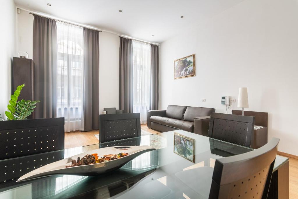 uma sala de estar com uma mesa de vidro e um sofá em Riverside Palace Suites em Praga
