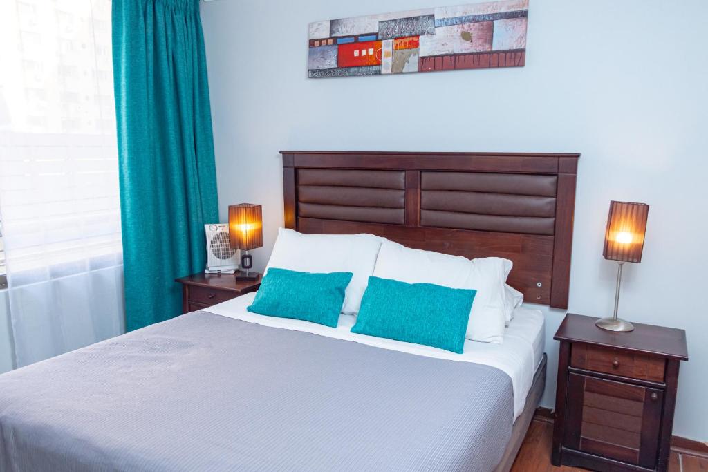 ein Schlafzimmer mit einem großen Bett mit zwei blauen Kissen in der Unterkunft Departamentos Amoblados Torre Tagle in Santiago