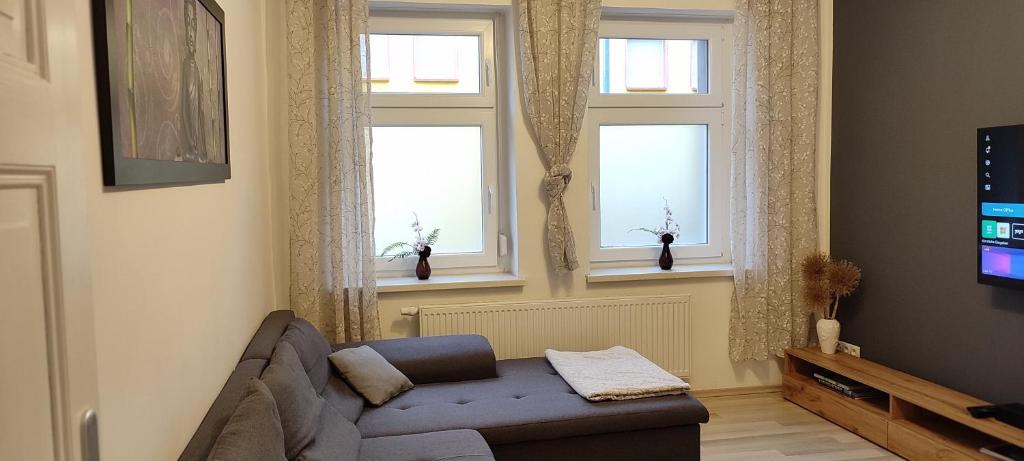 a living room with a couch and three windows at Ferienwohnung ASL in Aschersleben