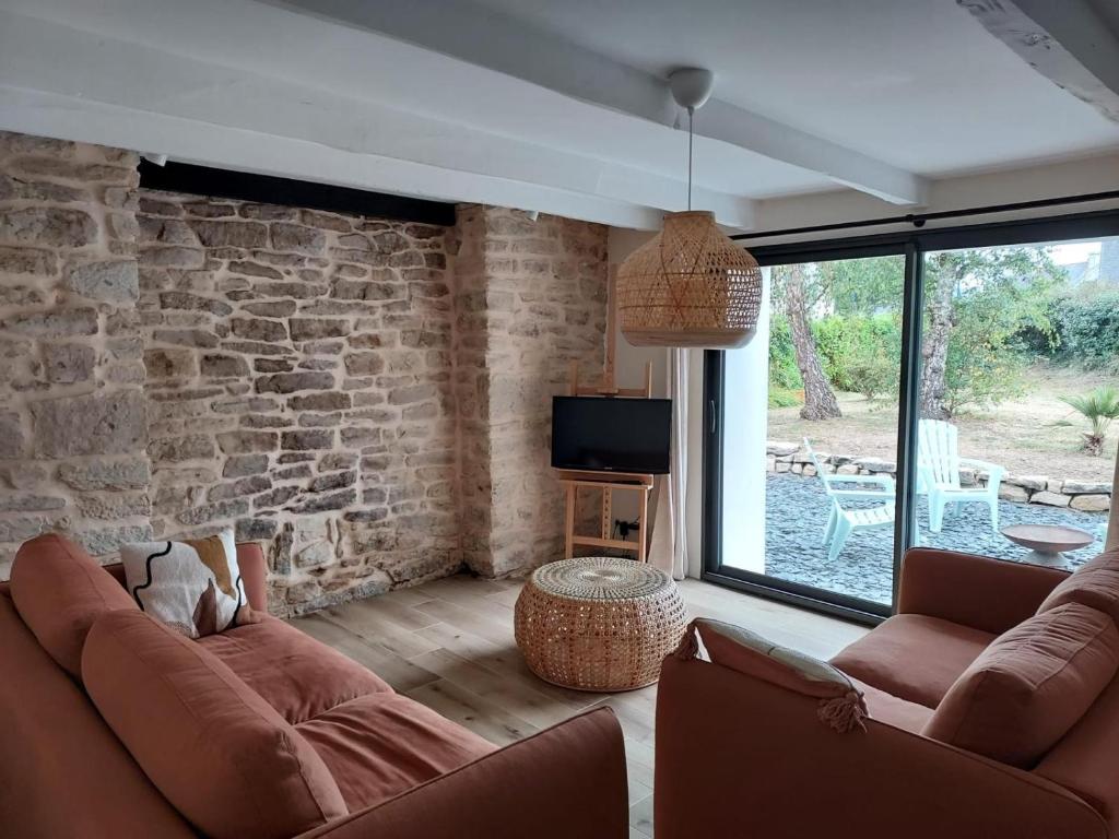 - un salon avec deux canapés et un mur en pierre dans l'établissement Maison de vacances - 3 chambres - proximité plage, à Bénodet
