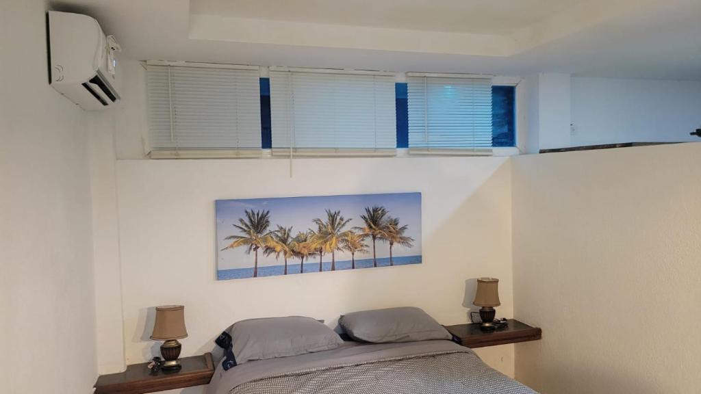 Chichiriviche的住宿－Apartamento tipo estudio，一间卧室设有一张床和两个棕榈树窗户。