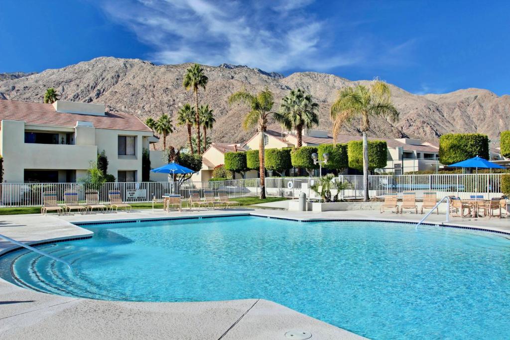 a swimming pool with palm trees and mountains in the background at Convenient & Cozy Downtown - A Ryson Property in Palm Springs