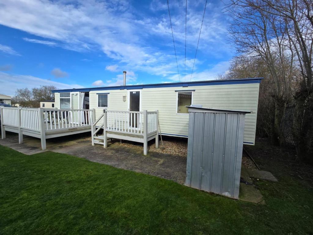 a white mobile home with a porch and two benches at The daxie 3-Bed caravan in Butlins Skegness in Skegness