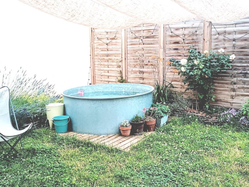 a large blue tub sitting in a yard with potted plants at Coup de cœur au jardin piscine - 400m gare Versailles & Paris in Saint-Cyr-lʼÉcole