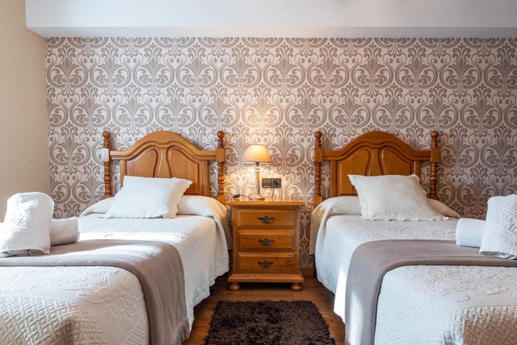 ein Schlafzimmer mit zwei Betten und einem Tisch mit Lampe in der Unterkunft La Carteria casa rural in Cangas de Onís