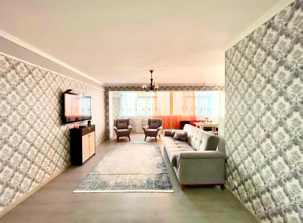 ein Wohnzimmer mit einem Sofa und einem TV in der Unterkunft ЖК «Caspyi Towers», 17-й микрорайон, 3 дом , 2 подъезд, 15 этаж , 114 кв. in Aqtau
