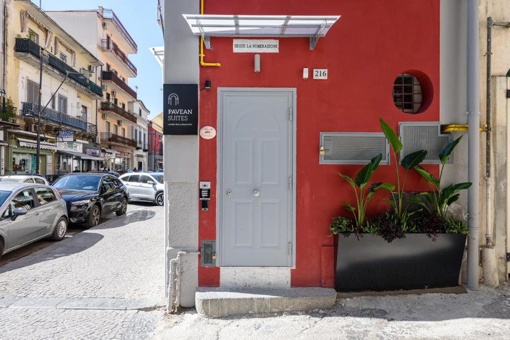 a red building with a white door on a street at Pavean Suites Frattamaggiore in Frattamaggiore