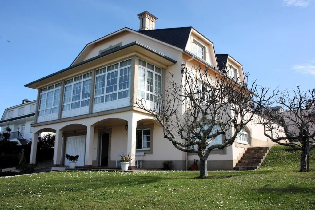 Cette grande maison blanche possède de nombreuses fenêtres. dans l'établissement Siete Playas Surf House, à Valdoviño