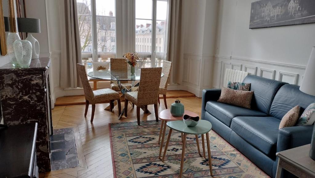 uma sala de estar com um sofá azul e uma mesa em Appartement avec belle vue sur la place du Martroi em Orléans