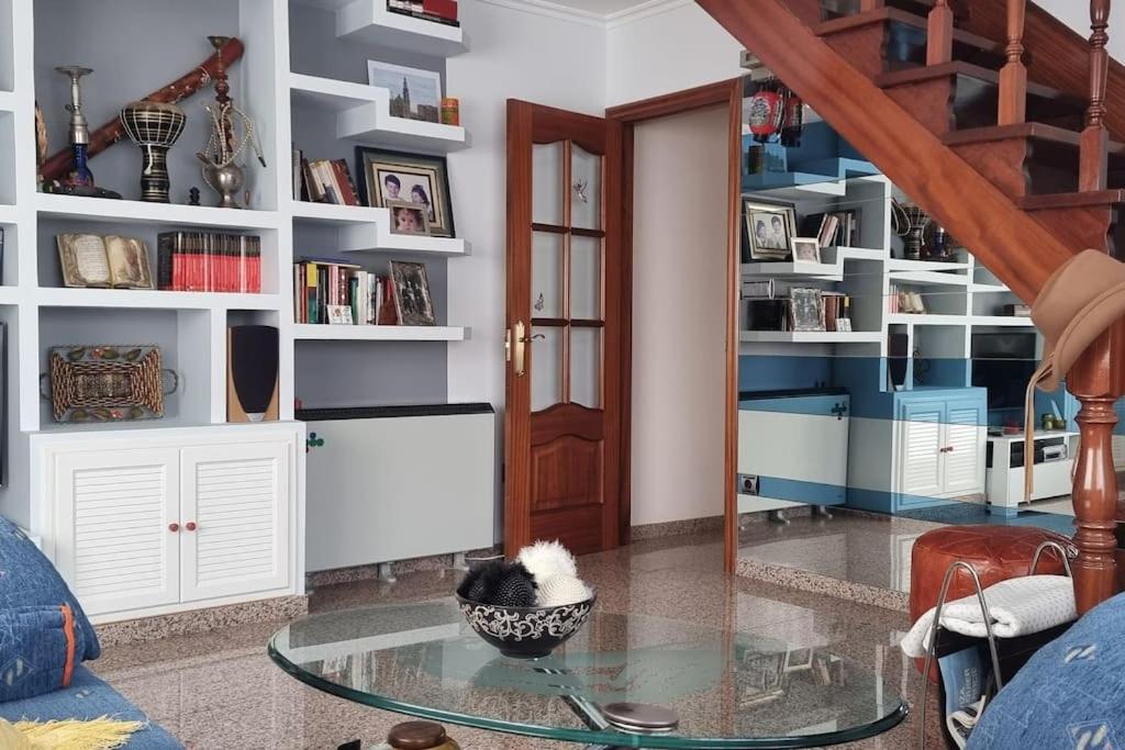 a living room with a glass table and white shelves at Duplex excelente situación in Narón