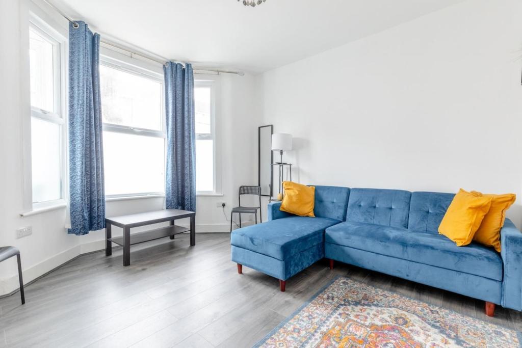 a living room with a blue couch and yellow pillows at Spacious & Newly Renovated 4BD House East Ham! in London