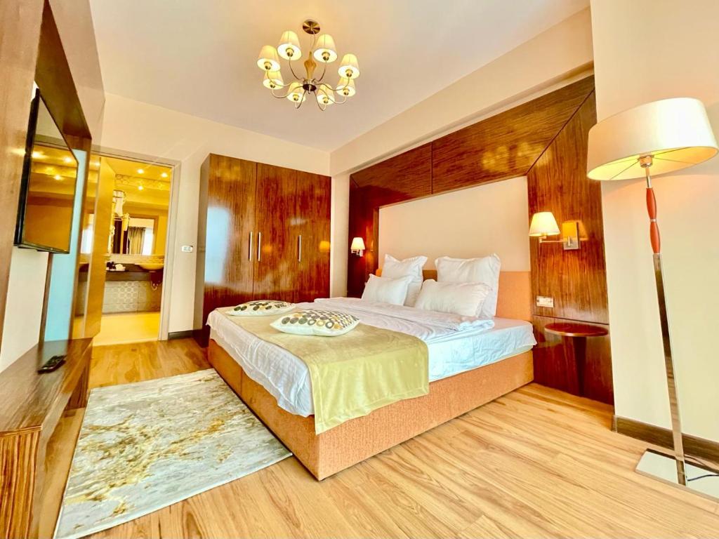 een slaapkamer met een groot bed en een kroonluchter bij Presidential Luxury Apartments With Amazing View - YamaLuxe in Boekarest