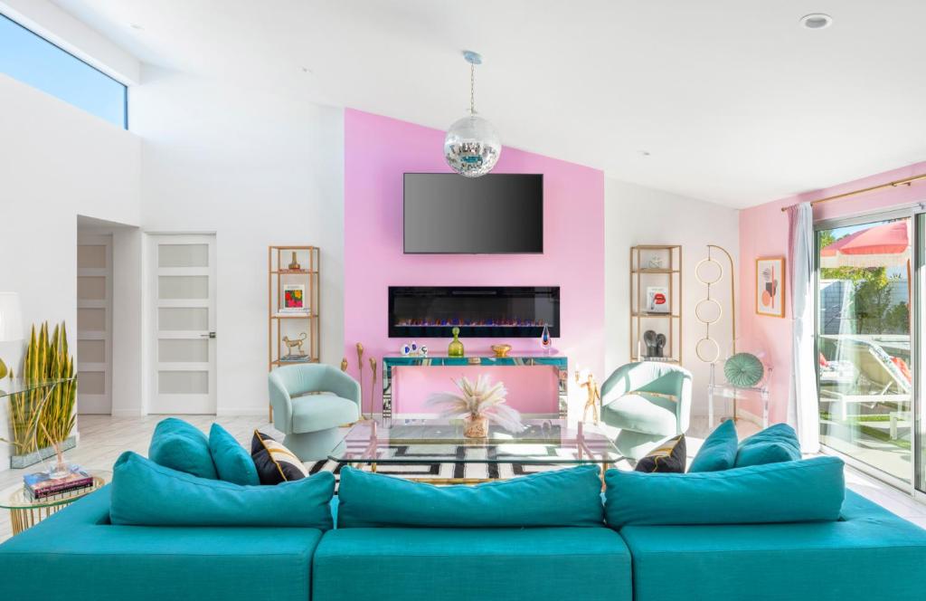 uma sala de estar com um sofá azul e uma parede rosa em Caliente Oasis - A Ryson Property em Palm Springs