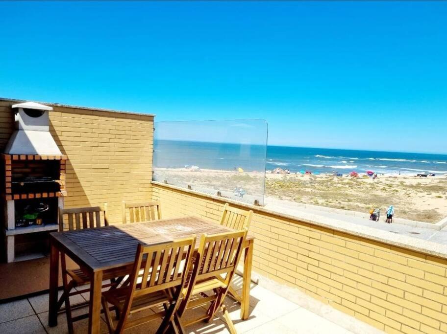Beach house Lavra في لافرا: طاولة وكراسي على شرفة مطلة على الشاطئ