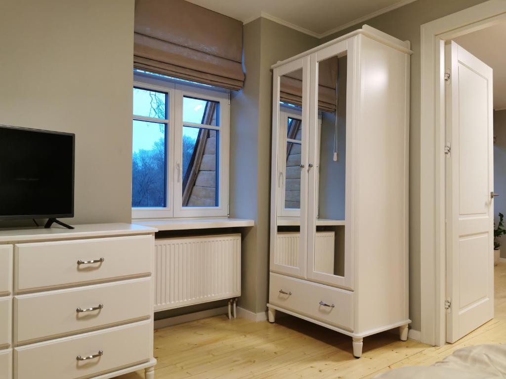 a bedroom with a white dresser and a tv at Vokės parko apartamentai in Vilnius
