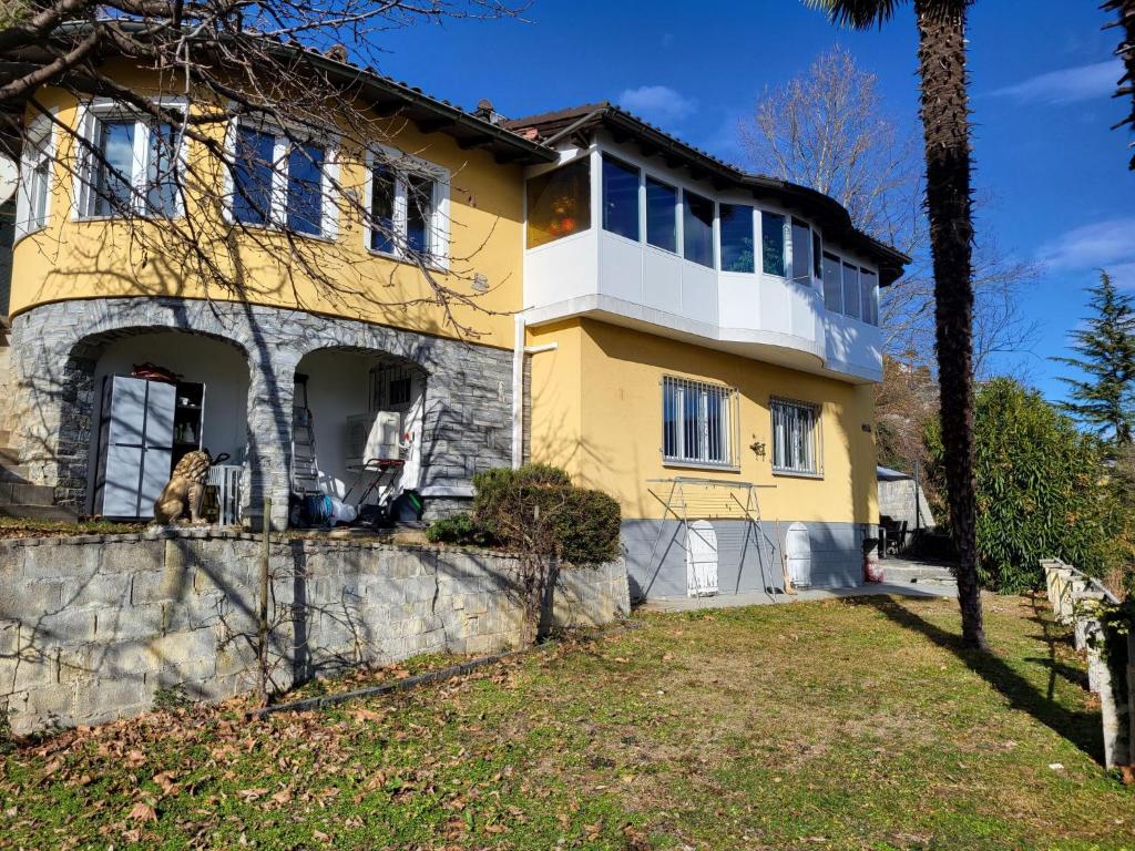 una casa gialla e bianca con una palma di Holiday Home Villa Miralago by Interhome ad Agno