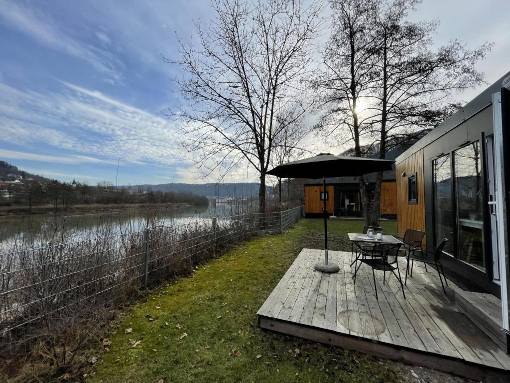 een tafel met een parasol op een houten terras naast een meer bij Holiday Home Tiny Haus Flussblick by Interhome in Riedenburg