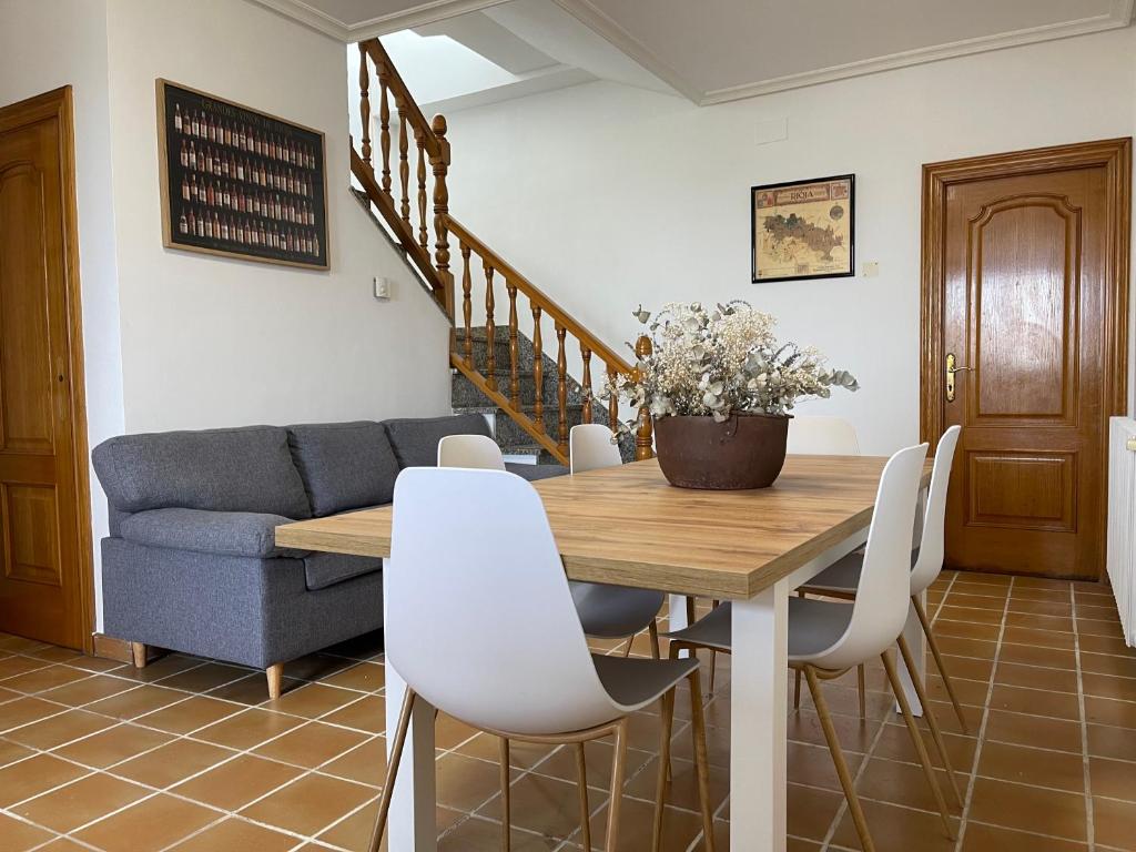 une salle à manger avec une table en bois et des chaises blanches dans l'établissement Alojamiento Rural El Castillo, à Agoncillo