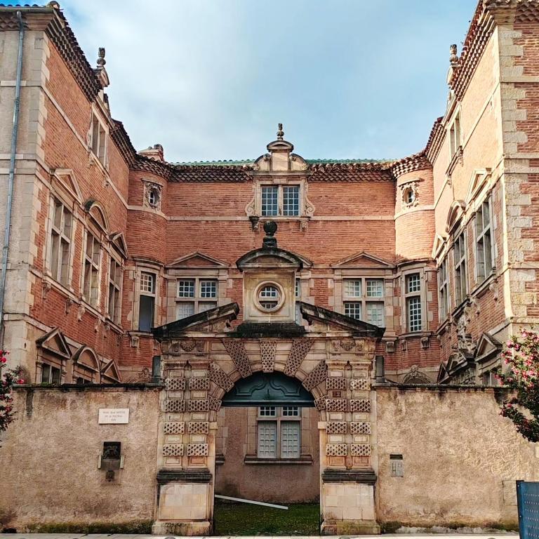 un grand bâtiment en briques avec une entrée voûtée dans l'établissement Appartement Bulle d'antan en cœur de ville - Monument classé historique - Grand Jaccuzi, à Castres