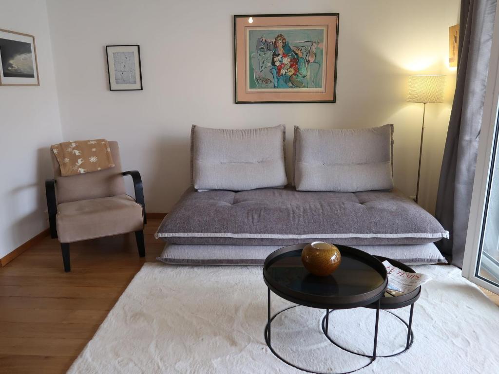 ein Wohnzimmer mit einem Sofa, einem Tisch und einem Stuhl in der Unterkunft Apartment Tasman S14-R by Interhome in Bouveret