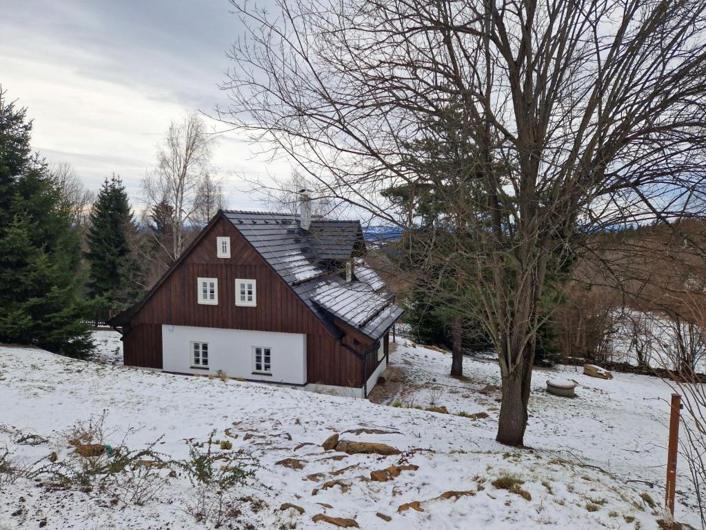 a red barn in a snow covered field at Holiday Home Roubenka Maleč by Interhome in Strašín