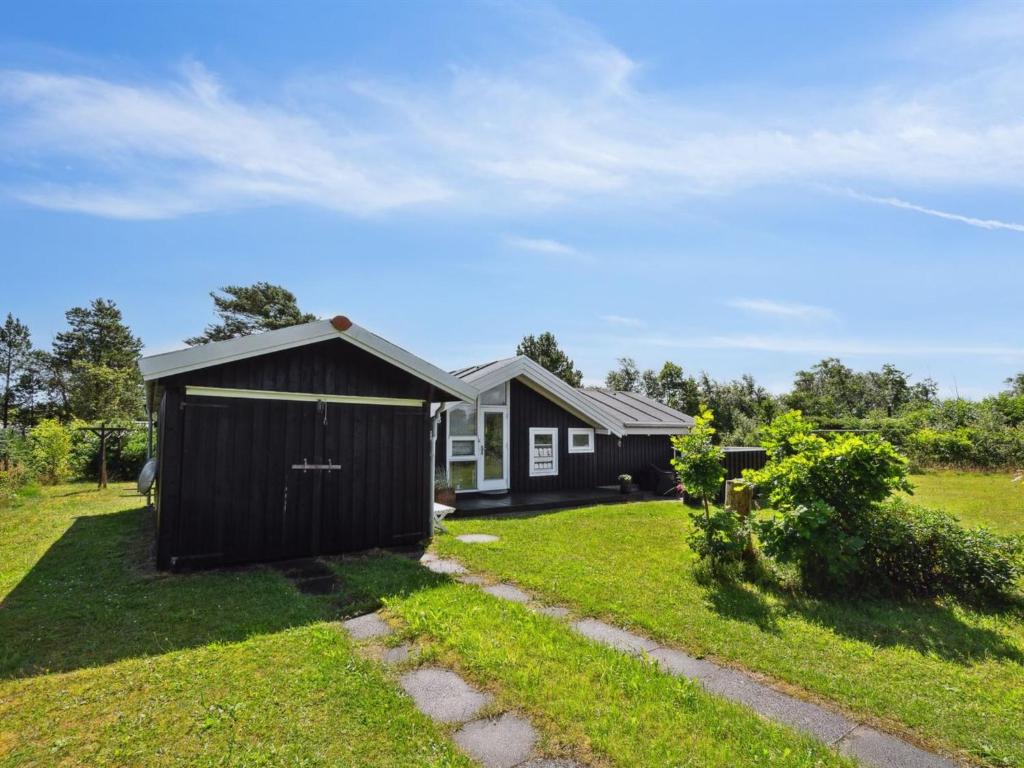 a small black house in a grassy yard at Holiday Home Santeri - 180m from the sea in NE Jutland by Interhome in Strandby