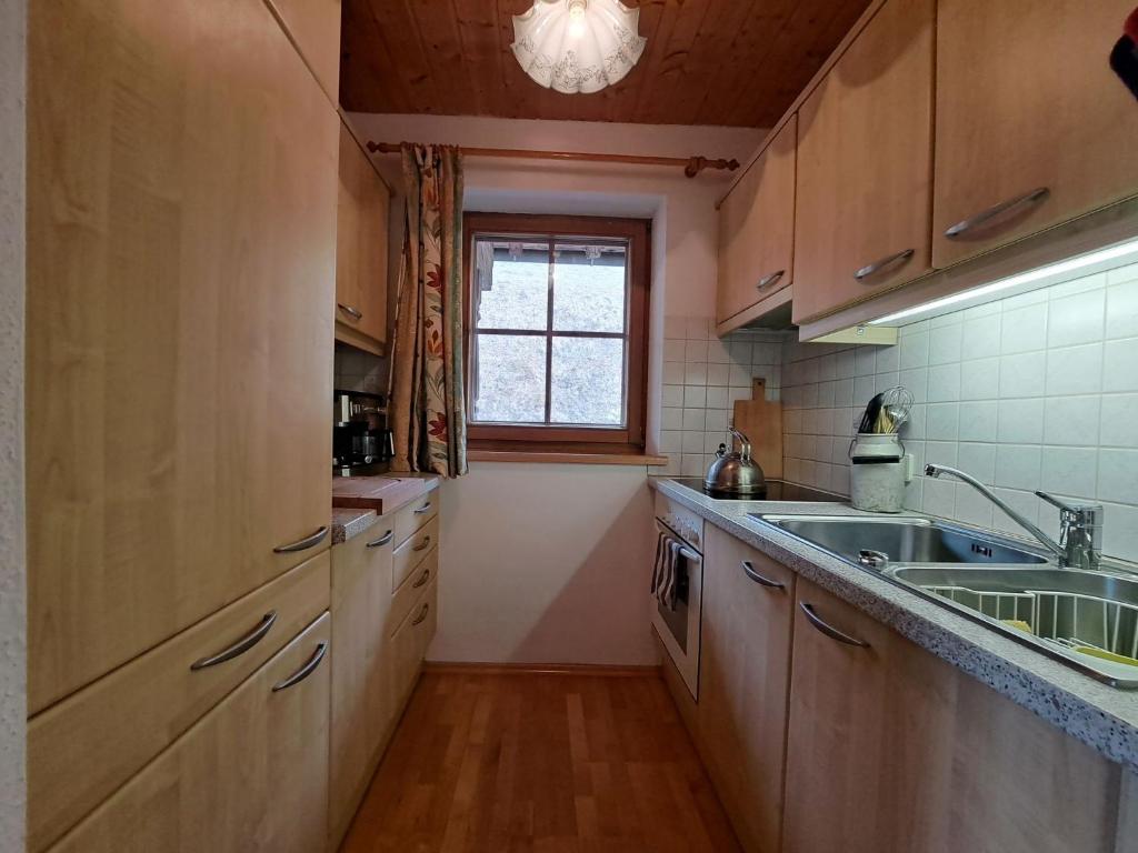 een keuken met houten kasten, een wastafel en een raam bij Apartment Bergpanorama by Interhome in Oberau