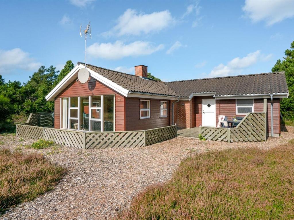 ein Haus mit einer großen Veranda auf einer Kieseinfahrt in der Unterkunft Holiday Home Svenger - 800m from the sea in NW Jutland by Interhome in Fjerritslev