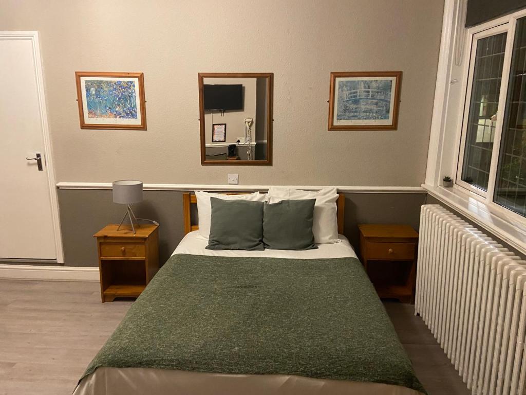 1 dormitorio con 1 cama con manta verde en The Swan Inn Pub en Isleworth