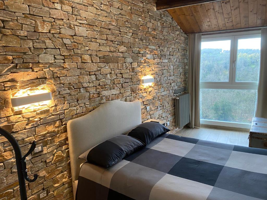 a bedroom with a stone wall and a bed with pillows at DOLCE VITA in Vignanello