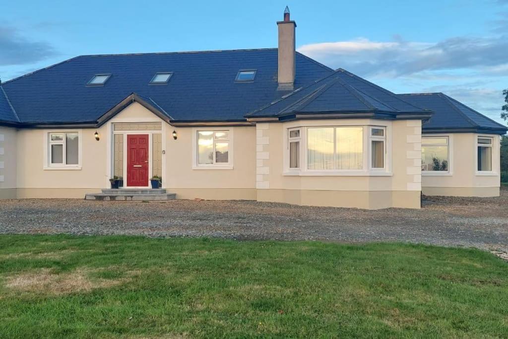 a house with a red door on a driveway at Modern Countryside apartment Killmallock Lodge in Enniscorthy