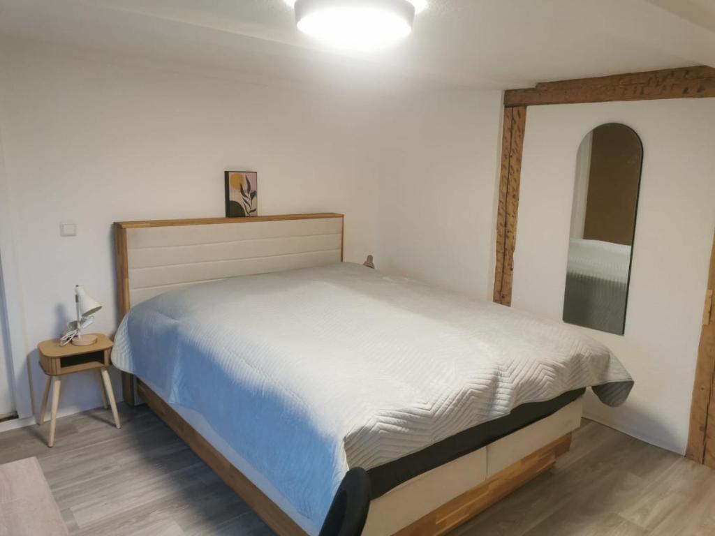a bedroom with a large bed and a night stand at Günstige, moderne Zimmer im Wanderparadies in Wernigerode
