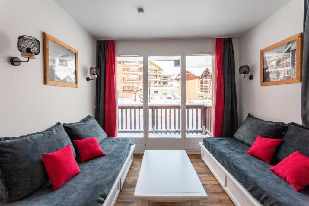 - un salon avec un canapé bleu et des oreillers rouges dans l'établissement Résidence Le Thabor - maeva Home - Appartement 3 Pièces 6 Personnes - Sélection MAE-8464, à Le Désert