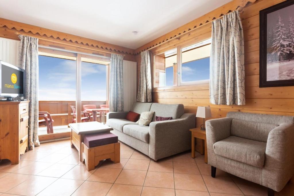 un salon avec un canapé et une chaise dans l'établissement Résidence Les Hauts Bois - maeva Home - Appartement 3 Pièces 8 Personnes - Sélection MAE-8034, à Aime La Plagne