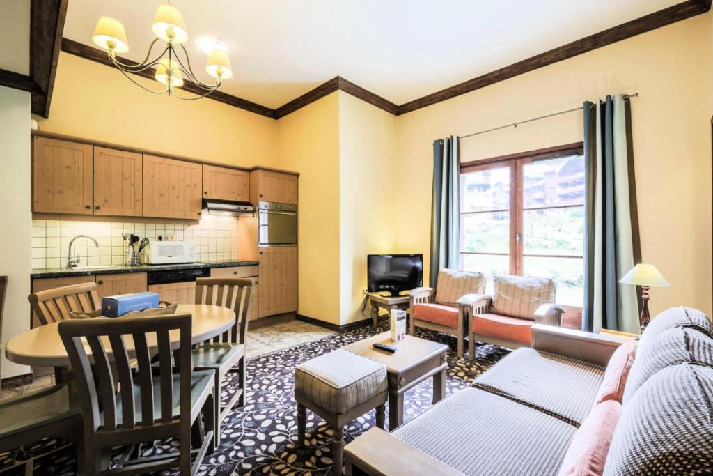 un salon avec un canapé, une table et une cuisine dans l'établissement Résidence Les Arcs 1950 Le Village - maeva Home - Appartement 2 pièces 6 personnes - Sélection MAE-6904, à Bourg-Saint-Maurice