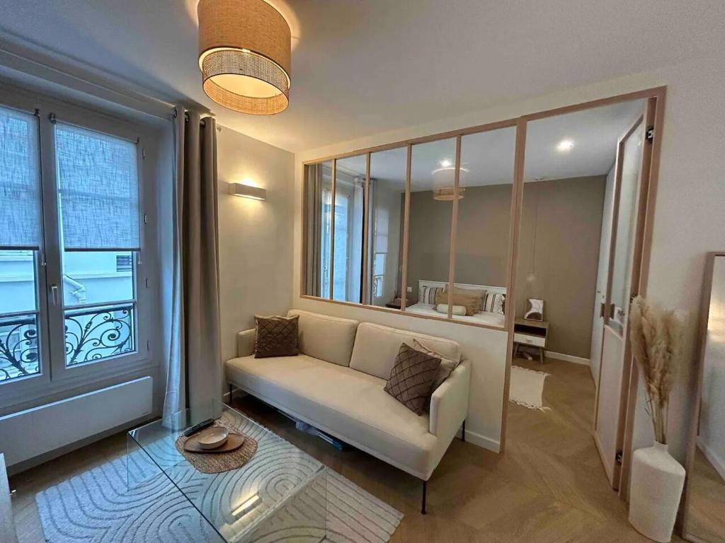 un salon avec un canapé et une grande fenêtre dans l'établissement Cocooning & Cosy Apartment in Center Paris 17, à Paris