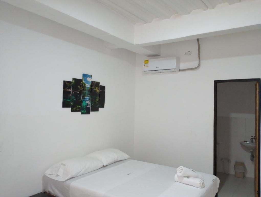 um quarto branco com uma cama e um lavatório em Hotel El refugio Doradal em Puerto Triunfo