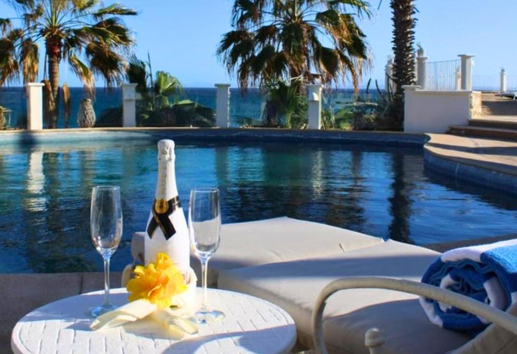 a table with two wine glasses next to a swimming pool at Punta Pescadero Paradise Hotel & Villas in Los Barriles