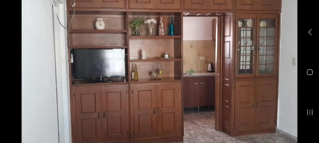 uma cozinha com armários de madeira e uma televisão de ecrã plano em LA CASA DE LILI Y JAVIER em Villa María