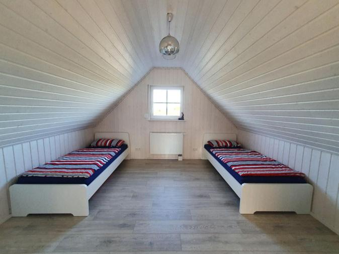 um quarto com 2 camas num sótão com uma janela em Haus Feldblick am Wasser em Berg